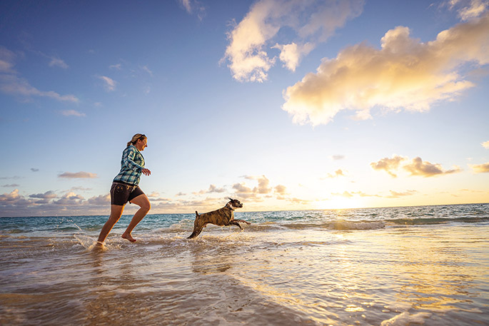 Woman and dog running on the beach